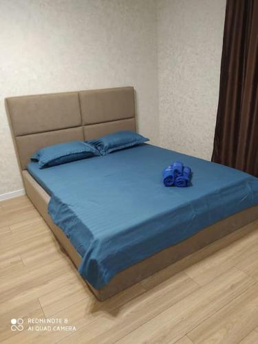 una cama con un animal de peluche azul sentado en ella en Абсолютно новая квартира en Kostanái
