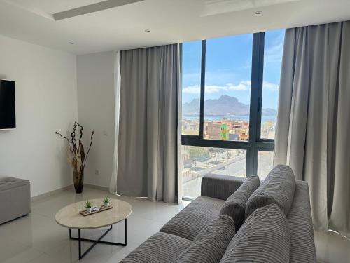 a living room with a couch and a large window at Sharksproperties Apartment in Mindelo