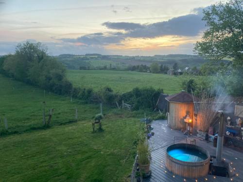 a large wooden building with a hot tub next to a field at Cottage with Hot Tube & private Sauna with panoramic view in Les Moutiers-en-Cinglais