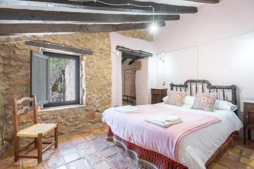 a bedroom with a large bed in a stone wall at Moli Colomer in La Torre d'En Besora