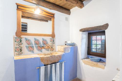 cocina con paredes azules y blancas y ventana en Moli Colomer en La Torre d'En Besora