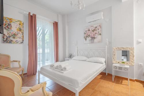 a white bedroom with a bed and a chair at Monte Verde Apartment 101 in Dhematorá