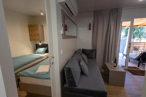 een slaapkamer met een bank en een bed en een balkon bij Adriakamp Mobilehome - Camp Soline in Biograd na Moru