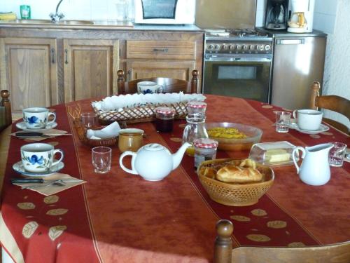 a table with a red table cloth with tea pots and cups at Maison Palu in Asson