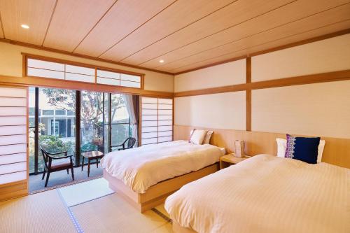 two beds in a room with a window at Tsubakikan in Aomori