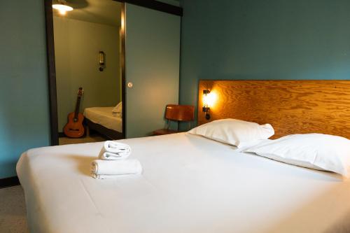 a bedroom with a white bed with a mirror and a guitar at Eklo Bordeaux Centre Bastide in Bordeaux