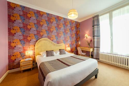 1 dormitorio con cama y pared de flores en The Originals Boutique, Hôtel Normandie, Auxerre en Auxerre