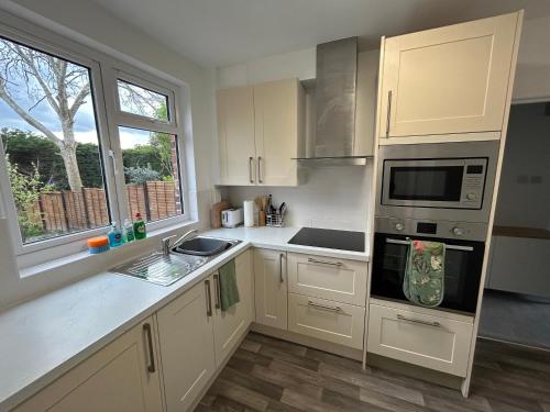 a kitchen with white cabinets and a sink and a microwave at Urban Escape Entire Apartment Near Uni and Hospital in Southampton