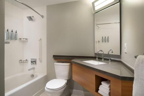 a bathroom with a toilet and a sink and a tub at Courtyard by Marriott Long Beach Downtown in Long Beach