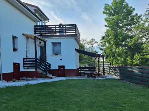 a white house with a porch and a fence at Holling apartman in Fertőboz