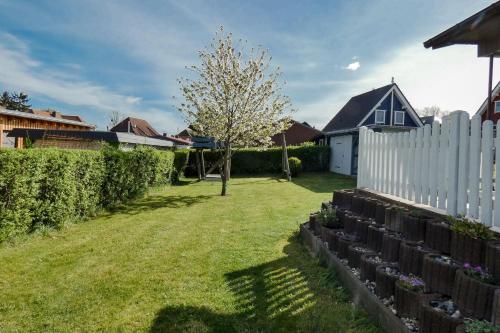a backyard with a white fence and a tree at Bungalow am Fleesensee in Unter Göhren