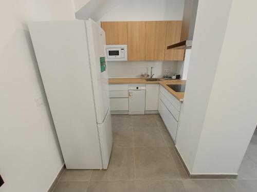 uma cozinha com armários brancos e um frigorífico branco em Lofts Vial Norte em Córdoba
