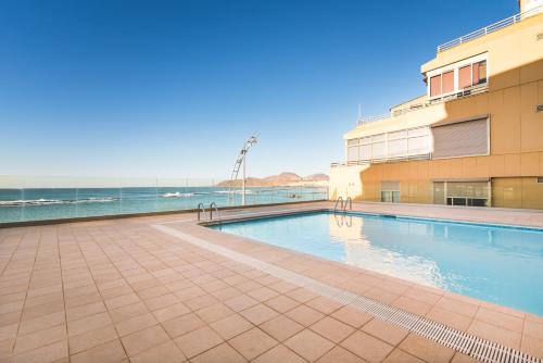 una piscina accanto a un edificio e l'oceano di Home2Book Design Las Canteras2 Beach a Las Palmas de Gran Canaria