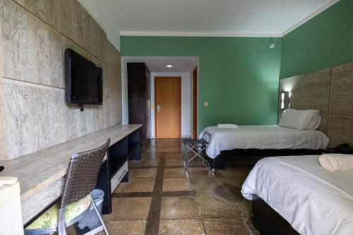 a hotel room with two beds and a flat screen tv at ARAGUAIA HOTEL in Barra do Garças