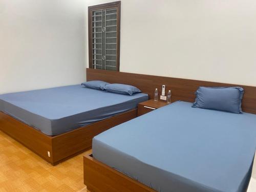 2 camas en una habitación con almohadas azules en Hằng Thường Hostel and Motorbikes Rental, en Ha Giang