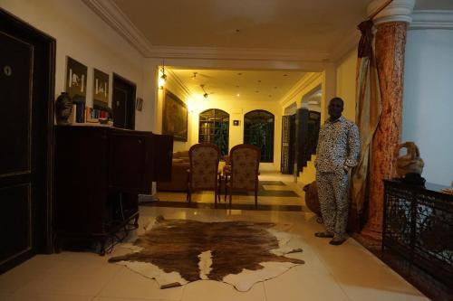 a man standing in a living room with a rug on the floor at Accra Royal Castle Apartments & Suites in Kwabenya