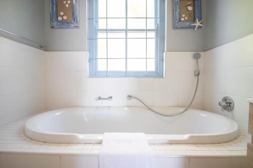 La salle de bains est pourvue d'une baignoire et d'une fenêtre. dans l'établissement Tides Holiday Home, à Paternoster