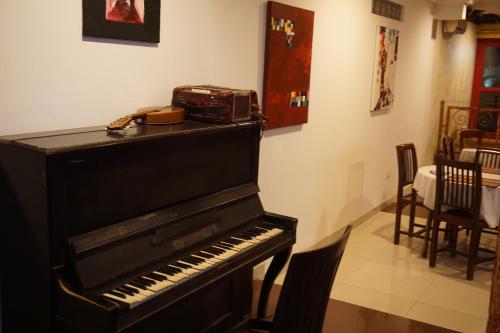 a black piano in a room with a table and chairs at Accra Royal Castle Apartments & Suites in Kwabenya