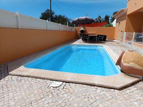 une piscine avec une table et un parasol dans l'établissement Holiday HouseV5 W/Pool & BBQ, à Albufeira