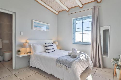 a white bedroom with a bed and a window at Tides Holiday Home in Paternoster