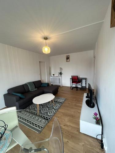a living room with a couch and a table at Appartement rénové et spacieux, Terrasse, 4 pers in Franconville