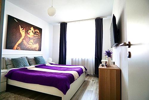 a bedroom with a purple bed and a large window at Relaxing Coresi Place in Braşov