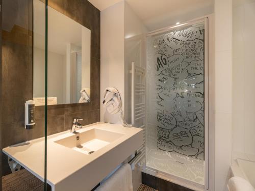 uma casa de banho com um lavatório e um espelho em B&B HOTEL Lorient Ploemeur em Ploemeur