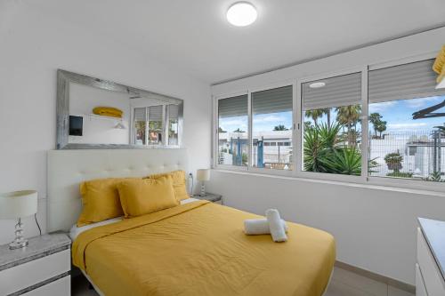 a bedroom with a bed with yellow sheets and windows at Costa del Silencio Tenerife Sur in Arona