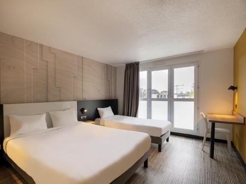 een hotelkamer met 2 bedden en een raam bij B&B HOTEL Lorient Ploemeur in Ploemeur