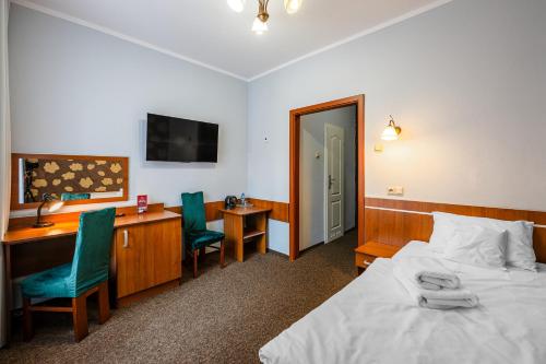 a bedroom with a bed and a desk with a computer at Hotel Bristol in Kielce