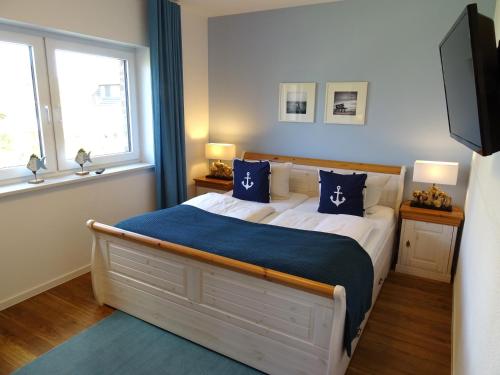 a bedroom with a bed with a blue blanket and two windows at Gode Wind Quartiere 4 in Dahme