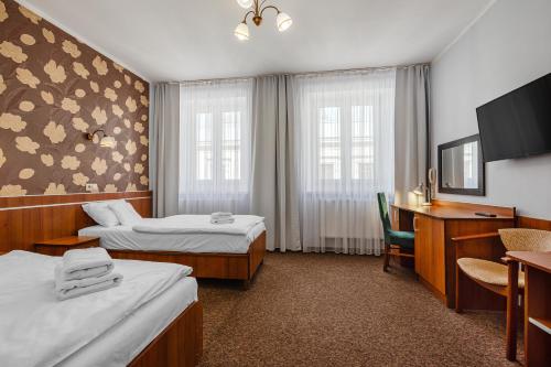 a hotel room with two beds and a desk at Hotel Bristol in Kielce