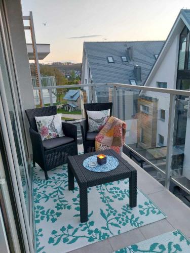 a balcony with two chairs and a table on a balcony at Apartament Cień Wiatru z Widokiem na Jezioro i Netflixem in Charzykowy