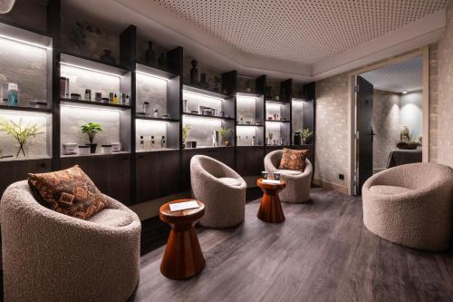 a waiting room with chairs and tables and shelves at Falcon Lodge by Alpine Residences in Méribel
