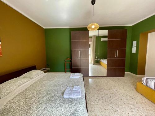 una camera da letto con pareti verdi e un letto con asciugamani di La casetta a San Marco Evangelista