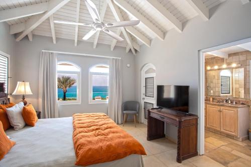 una camera con letto, ventilatore a soffitto e TV di Villa Mongoose - vue exceptionnelle a Saint Martin