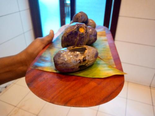 a person holding a plate of fruit on a table at Bau rivage hotel in Akwa