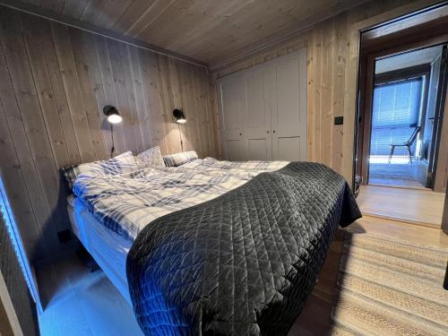 - une chambre avec un lit dans une pièce dotée de murs en bois dans l'établissement Golsfjellet - new modern cabin with fantastic view, à Golsfjellet