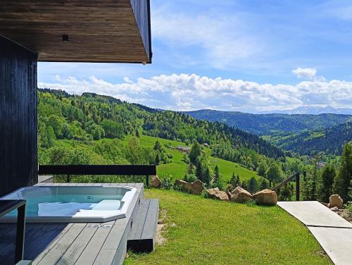 a hot tub on a deck with a view of the mountains at Bacówki Resort in Ochotnica Górna