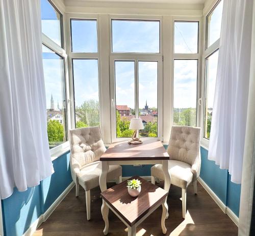 um quarto com duas cadeiras, uma mesa e janelas em Hotel Rummeni em Borkum