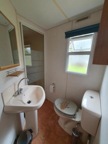 une salle de bain avec un lavabo et des toilettes et une fenêtre dans l'établissement Camping du Lac, à Égletons