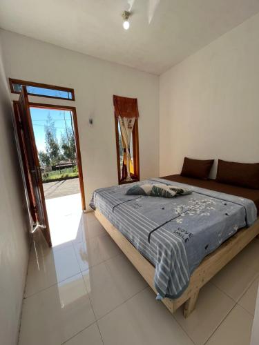 um quarto com uma cama e uma grande janela em Gangga Guest House Bromo em Ngadisari