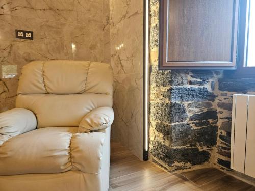 una sedia in pelle in una stanza con parete in pietra di 27A01 Casa Uría - Cam. Santiago a Berducedo
