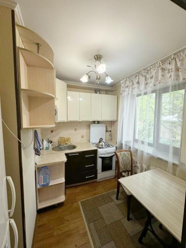 uma cozinha com armários brancos, uma mesa e uma sala de jantar em Квартиры рядом с Аэропортом города Алматы em Turksib