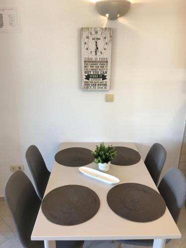 a table with four chairs and a clock on the wall at Apartmani Samec in Novalja