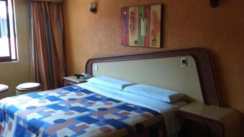 a bedroom with a bed with a blue and white comforter at Hotel Aeropuerto in Toluca
