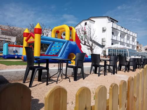 un parque infantil con sillas y equipo de juegos en Hotel Biser, en Pag