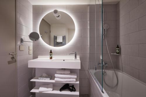 a bathroom with a sink and a mirror and a tub at Aparthotel Adagio Original Toulouse Centre La Grave in Toulouse