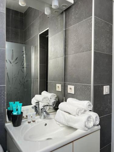 une salle de bain avec un lavabo, un miroir et des serviettes dans l'établissement Praia Bohème, à Mauguio