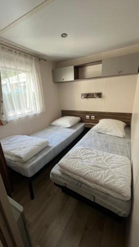 une chambre avec deux lits et une fenêtre dans l'établissement Mobilhome climatisé, 6 personnes camping les embruns, à Lège-Cap-Ferret